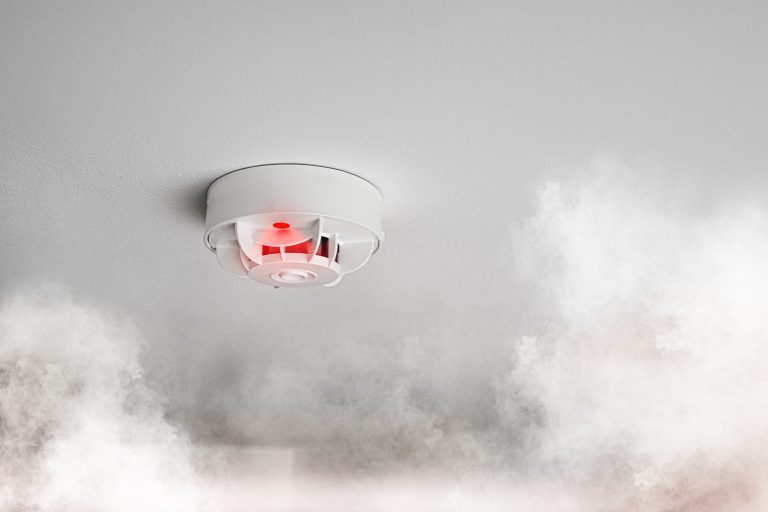 close-up of smoke alarm or smoke detector in home going off with thick smoke
